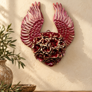 Handmade pink and gold floral winged tin heart wall decor in a warm MexRoots-style home